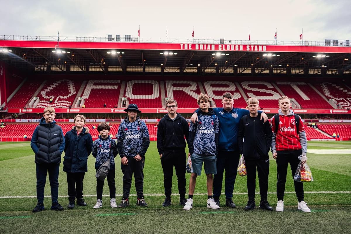 Step Out Stay Out young people standing pitchside at Nottingham Forest's City Ground with the Brian Clough Stand in the background